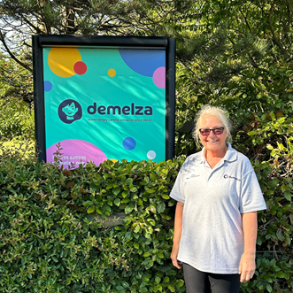 Healthcare Assistant Anne stood by a Demelza sign