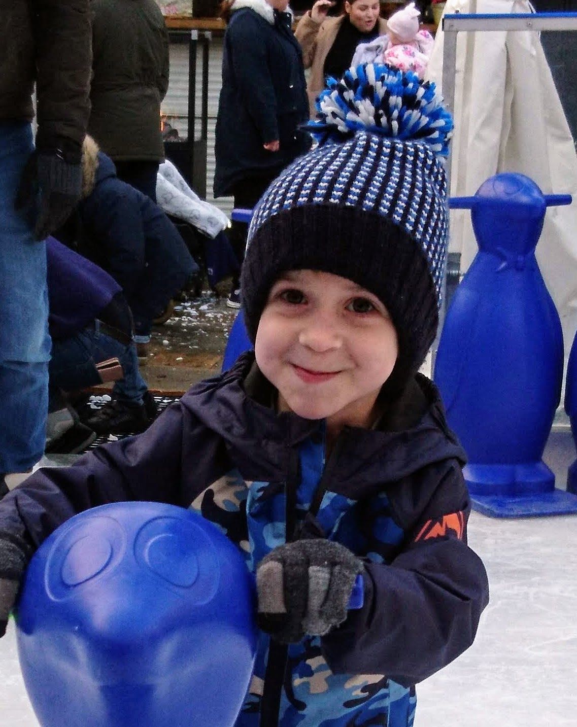 Zak enjoying ice skating, wearing a blue bobble hat.