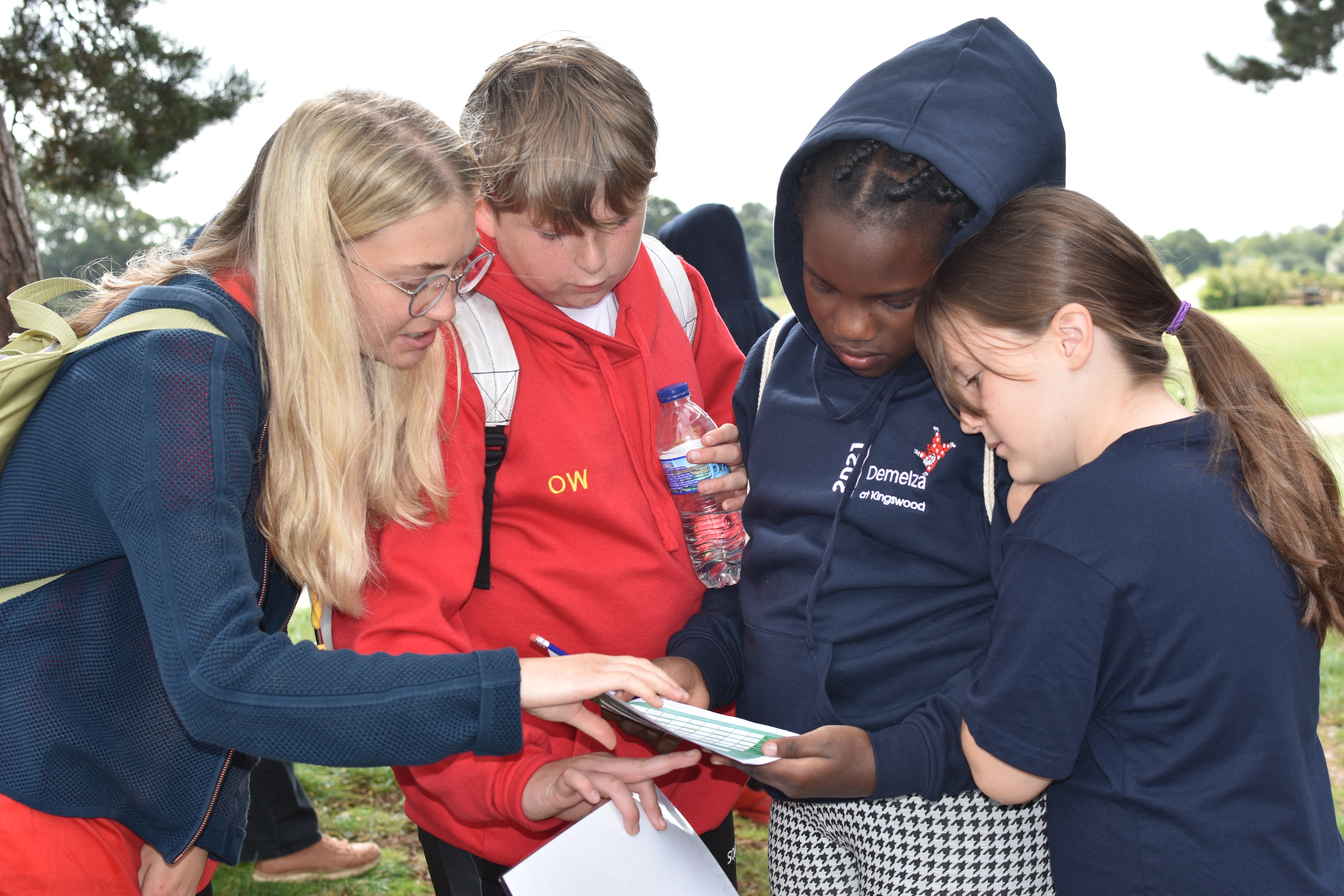 Oliver and other children gather around a piece of paper as they prepare for their next activity.