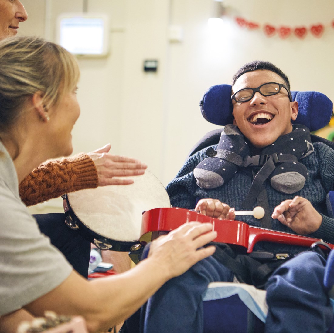 a teenaged boy smiling during his music therapy session with a demelza healthcare assistant and his parent