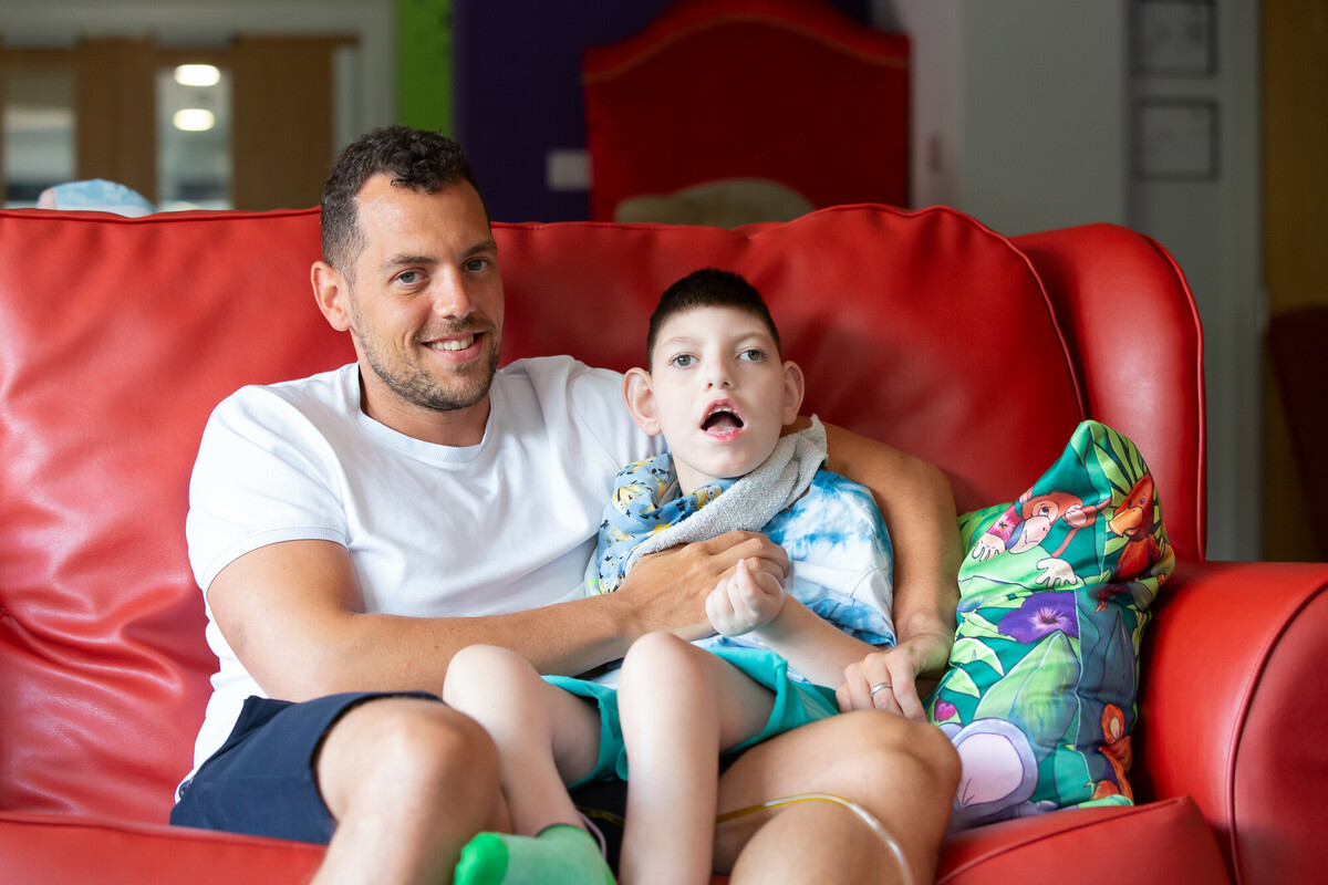 Father and son sitting on a red sofa.