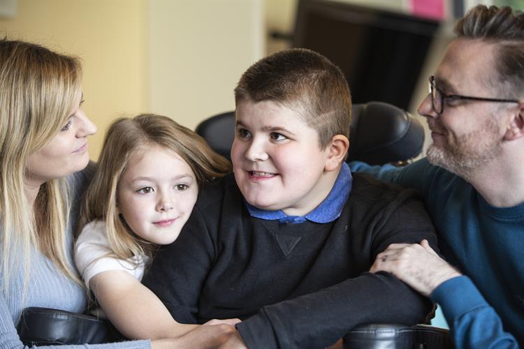 Curtis is sitting, surrounded by his mum, dad and little sister.